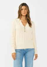 [Color: Peach] A front facing image f a brunette model wearing a cream fuzzy pullover sweater with a v neckline, button front, and long sleeves. 