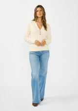 [Color: Peach] A front facing image f a brunette model wearing a cream fuzzy pullover sweater with a v neckline, button front, and long sleeves. 