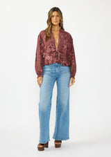 [Color: Wine/Dusty Rose] A front facing image of a brunette model wearing a bohemian burgundy floral tie front top with a deep v neckline and long sleeves. Styled with light wash denim and brown block heels. 