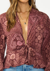 [Color: Wine/Dusty Rose] A detail image of a brunette model wearing a bohemian burgundy floral tie front top with a deep v neckline and long sleeves. 