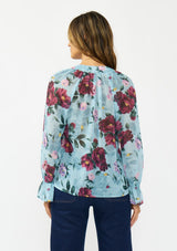 [Color: Blue/Burgundy] A back facing image of a brunette model wearing a blue and burgundy floral blouse with a tie neck detail and button front. Styled with dark wash denim. 