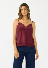 [Color: Merlot] A front facing image image of a brunette model wearing a burgundy lace cami with spaghetti straps. Styled with dark wash denim. 