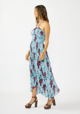 [Color: Blue/ Burgundy] A side facing image of a brunette model wearing a blue and burgundy floral plisse midi dress with a halter neckline and a shirred bodice.  