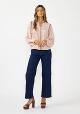 [Color: Mauve] A front facing image of a brunette model wearing a pink bohemian blouse with embroidery, a button front, and pintuck detailing. Styled with a dark wash denim with patch pockets. 