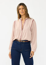 [Color: Mauve] A front facing image of a brunette model wearing a pink bohemian blouse with embroidery, a button front, and pintuck detailing. Styled tucked into a dark wash denim with patch pockets. 