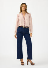 [Color: Mauve] A front facing image of a brunette model wearing a pink bohemian blouse with embroidery, a button front, and pintuck detailing. Styled with a dark wash denim with patch pockets and brown block heels.