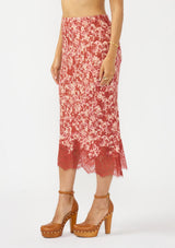 [Color: Wine/Dusty Rose] A side facing image of a red and white midi skirt with lace trim. Styled with a brown platform heel. 