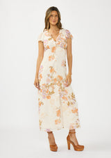 [Color: Ivory/Rust] A front facing image of a brunette model wearing a floral maxi dress with short flutter sleeves, a ruffled v neckline, button front, and a front slit. Styled with brown platform heels. 