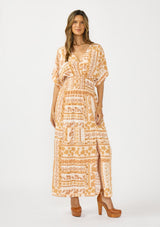 [Color: Taupe/Natural] A front facing image of a brunette model wearing a brown floral bohemian maxi dress with short dolman sleeves, a v neckline, smocked waist, and a front slit. 