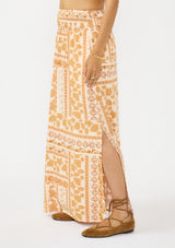 [Color: Taupe/Natural] A side facing image of a brown floral bohemian maxi skirt with a smocked waist and side slits. 