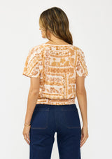 [Color: Taupe/Natural] A back facing image of a brunette model wearing a bohemian brown floral top with a v neckline, short sleeves, and a tie front detail.