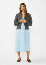 [Color: Charcoal] A front facing image of a brunette model wearing a grey pointelle knit button front cardigan with a round neckline and long puff sleeves. Styled over a blue midi cotton dress. 