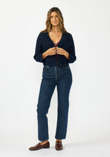 [Color: Navy] A front facing image of a brunette model wearing a navy cropped knit cardigan with sequins and a button front. 