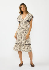 [Color: Natural/Olive] A front facing image of a brunette model wearing a beige and black floral print midi dress with short flutter sleeves, a v neckline, and a ruffle trimmed hem. 