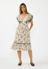 [Color: Natural/Olive] A front facing image of a brunette model wearing a beige and black floral print midi dress with short flutter sleeves, a v neckline, and a ruffle trimmed hem. 