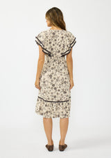 [Color: Natural/Olive] A back facing image of a brunette model wearing a beige and black floral print midi dress with short flutter sleeves, a v neckline, and a ruffle trimmed hem. 