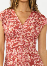 [Color: Wine/Dusty Rose] A detail image of a brunette model wearing a wine floral print midi dress with a ruched bodice, v neckline, and short flutter sleeves. 