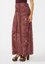 [Color: Wine/Dusty Rose] A side facing image of a brunette model wearing a bohemian burgundy floral skirt with drawstrings, styled with brown block heels. 