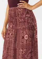 [Color: Wine/Dusty Rose] A detail image of a brunette model wearing a bohemian burgundy floral skirt with drawstrings, styled with brown block heels. 
