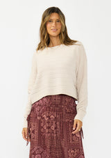 [Color: Birch] A front facing image of a brunette model wearing an off white chenille sweater with a round neck and long sleeves with dropped shoulders. Styled with the burgundy paisley  bohemian maxi skirt. 