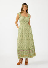 [Color: Olive/Rose] A front facing image of a brunette model wearing a green bohemian floral maxi dress with cap sleeves, a square neckline, elastic waist, and a tiered skirt with ruffle trims.