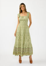 [Color: Olive/Rose] A front facing image of a brunette model wearing a green bohemian floral maxi dress with cap sleeves, a square neckline, elastic waist, and a tiered skirt with ruffle trims.