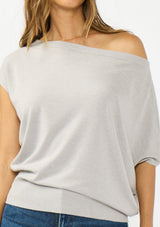 [Color: Light Heather Grey] A detail image a brunette model wearing an off the shoulder sweater top with short sleeves and a fitted ribbed hem. 