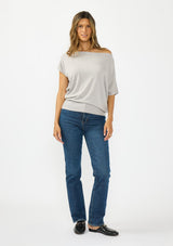 [Color: Light Heather Grey] A front facing image a brunette model wearing an off the shoulder sweater top with short sleeves and a fitted ribbed hem. Styled with dark wash denim and black loafers. 