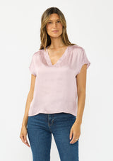 [Color: Dusty Orchid] A front facing image of a brunette model wearing a pink satin top with an embroidered trim and short dolman sleeves. 