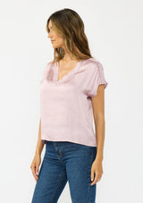[Color: Dusty Orchid] A side facing image of a brunette model wearing a pink satin top with an embroidered trim and short dolman sleeves. 