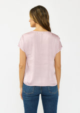 [Color: Dusty Orchid] A back facing image of a brunette model wearing a pink satin top with an embroidered trim and short dolman sleeves. 