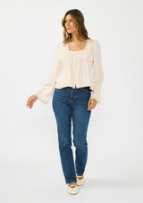 [Color: Petal] A front facing image of a brunette model wearing an off white lace long sleeve top with a scoop neckline and button front. Styled with dark wash straight leg denim. 