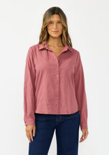 [Color: Rose] A front facing image of a brunette model wearing a pink shirt with a classic collar and button front. Styled with a dark wash denim with patch pockets. 