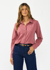 [Color: Rose] A front facing image of a brunette model wearing a pink shirt with a classic collar and button front. Styled with a dark wash denim with patch pockets. 