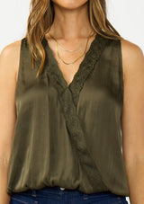 [Color: Olive] A detail image of a brunette model wearing a olive green sleeveless top with an embroidered trim, elastic hem, and a surplice front. 