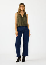 [Color: Olive] A front facing image of a brunette model wearing a olive green sleeveless top with an embroidered trim, elastic hem, and a surplice front. Styled with a dark wash denim and black boots. 