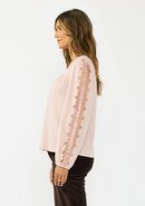 [Color: Shell] A side facing image of a brunette model wearing a pink embroidered top with mesh detail. Styled with a dark brown corduroy. 