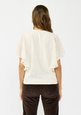 [Color: Vanilla] A back facing image of a brunette model wearing an ivory embroidered surplice top with flutter sleeves, an elastic hemline, and a tie detail. Styled with dark brown corduroys. 
