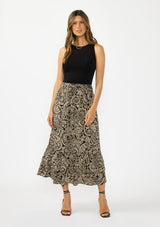 [Color: Black/Natural] A front facing image of a model wearing a tan and lack boho paisley skirt with a tiered ruffle hem. Styled with a black tank top and black strappy heels. 