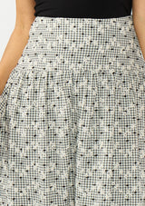 [Color: Black] A detail image of an black and white embroidered checkered  midi skirt with a side zipper. 