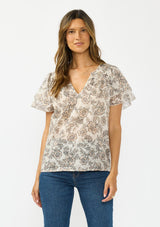 [Color: Cream/Black] A front facing image of a brunette model wearing a cotton floral top with double flutter sleeves and a split v neckline. 