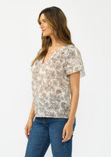 [Color: Cream/Black] A side facing image of a brunette model wearing a cotton floral top with double flutter sleeves and a split v neckline. 