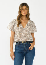 [Color: Cream/Black] A front facing image of a brunette model wearing a cotton floral top with double flutter sleeves and a split v neckline. 