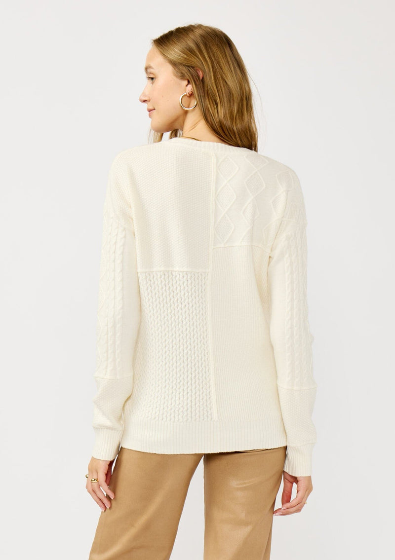 [Color: Cloud] A back facing image of a blonde model wearing a white cozy mix knit pullover sweater with a classic crew neckline. Lightweight and warm for casual outings or the office. 