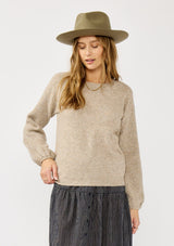 [Color: Heather Cement] A front facing image of a blonde model in a beige crewneck pullover sweater with ribbed blouson sleeves. A versatile knit ideal for styling with skirts or trousers for a chic, polished outfit.