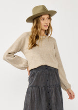 [Color: Navy/Taupe] A detail image of a blonde model wearing a navy gingham skit with a button front and a smocked elastic waist at the back. A boho fall skirt paired with a sweater for the fall season. 