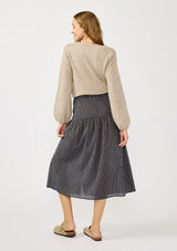 [Color: Navy/Taupe] A back facing image of a blonde model wearing a navy gingham skit with a button front and a smocked elastic waist at the back. A boho fall skirt paired with a sweater for the fall season. 