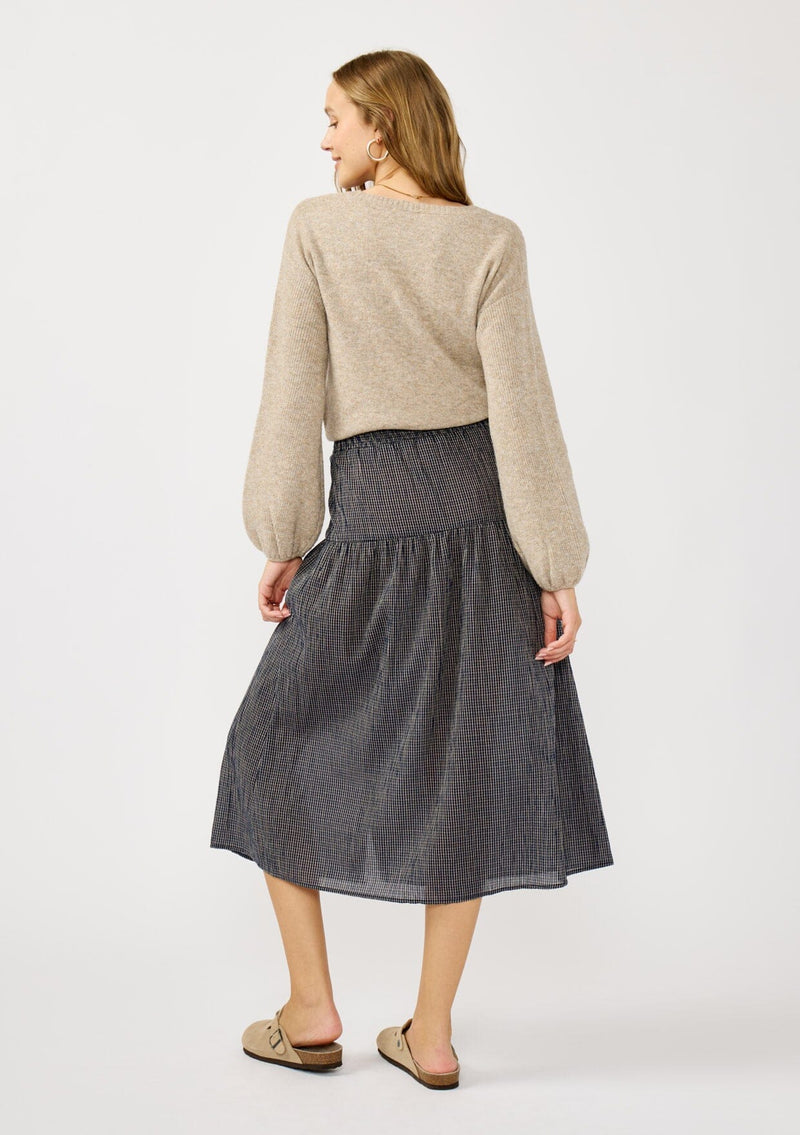 [Color: Navy/Taupe] A back facing image of a blonde model wearing a navy gingham skit with a button front and a smocked elastic waist at the back. A boho fall skirt paired with a sweater for the fall season. 