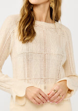 [Color: Blush] A detail image of a blonde model wearing a fuzzy open knit pullover sweater with a crew neckline, long sleeves, and a flutter cuff. Lightweight and breezy for the fall season. 