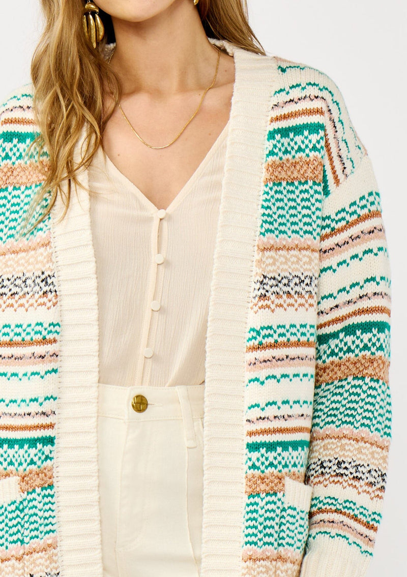 [Color: White/Green] A detail image of a blonde model wearing a green and brown striped knit cardigan with a contrasting ribbed trim. Featuring long cozy sleeves and an open front for easy layering. A boho inspired cardigan for the fall season. 